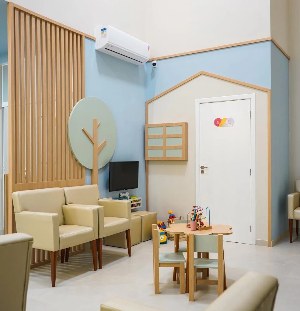 Sala de espera infantil da Clínica Crescer, com mesinha, cadeirinhas, brinquedos e parede azul claro