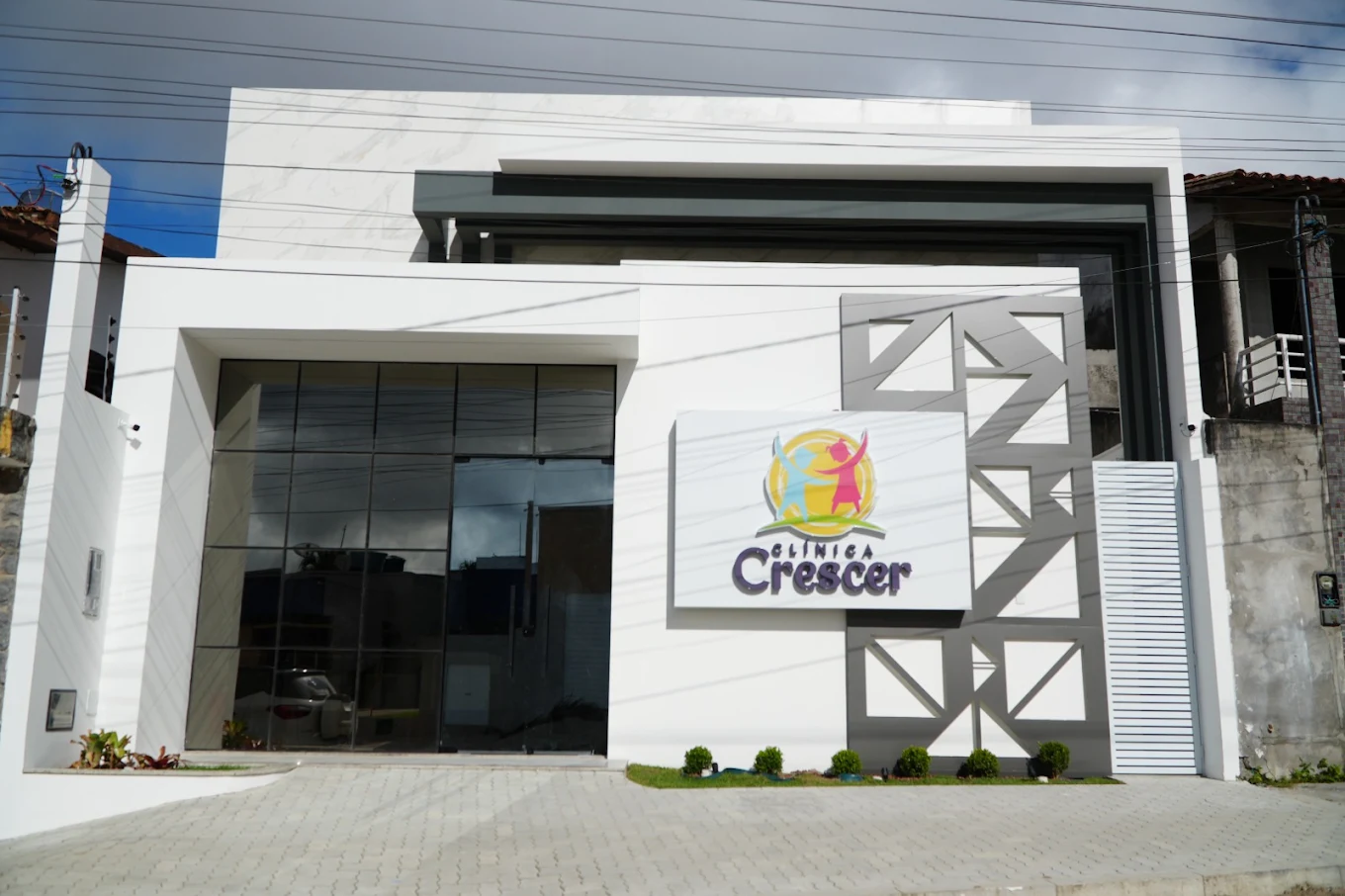 Fachada branca e moderna da Clínica Crescer em Serrinha, com o logo em destaque